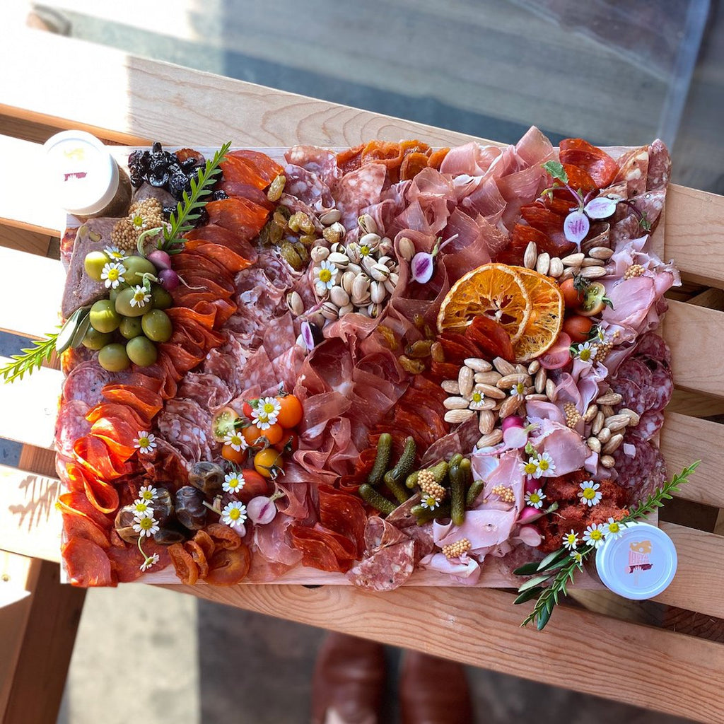 Lady & Larder Charcuterie board with all the cured meats, grainy mustard, seasonal stone fruit, olives, and flowers 