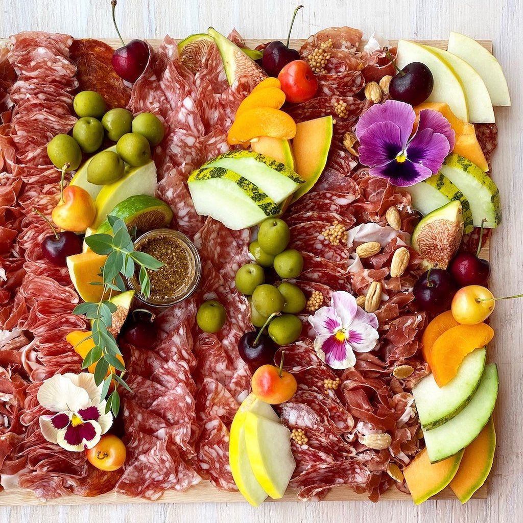 Lady & Larder Charcuterie board with all the cured meats, grainy mustard, seasonal stone fruit, olives, and flowers 