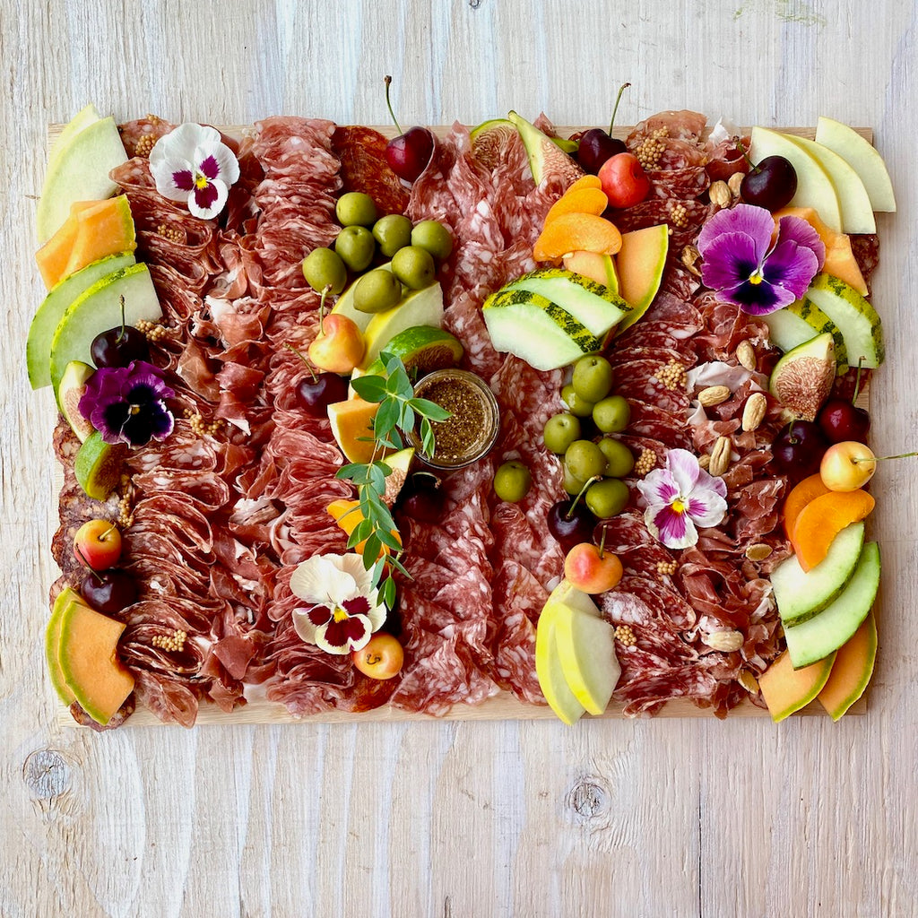 Lady & Larder Charcuterie board with all the cured meats, grainy mustard, seasonal stone fruit, olives, and flowers 