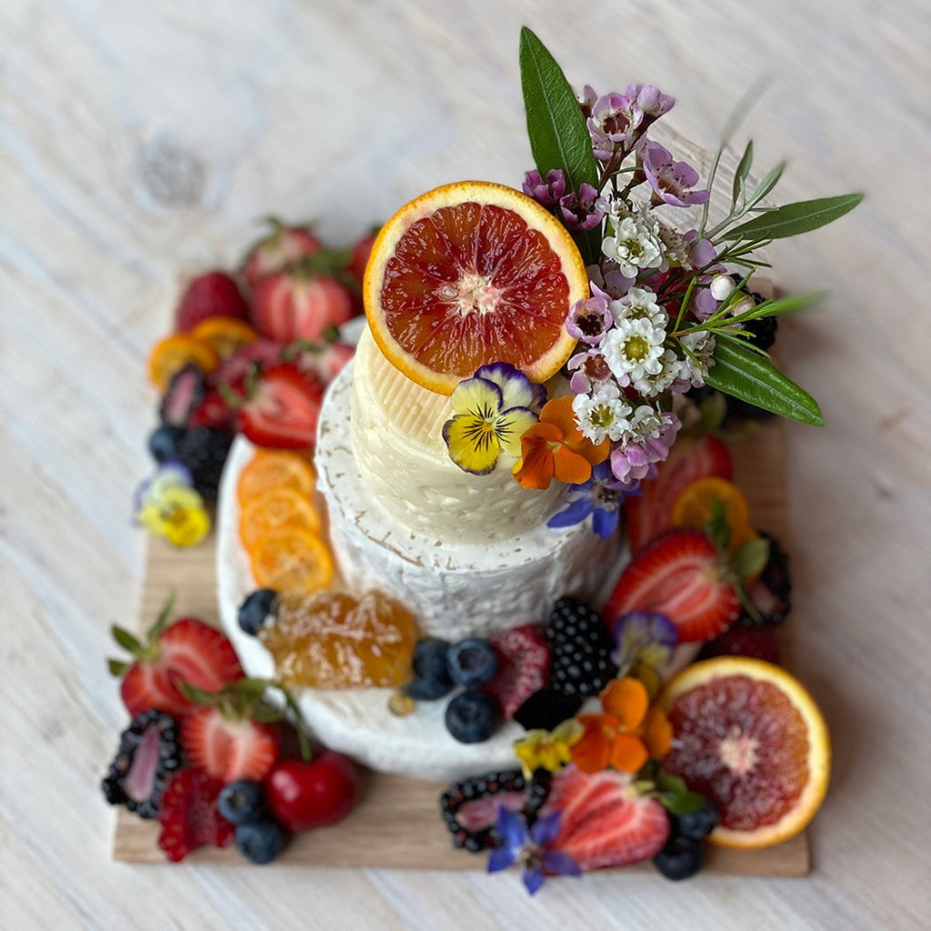 Lady & Larder cake made out of cheese and garnished with fresh fruit and flowers