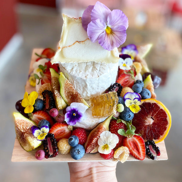 Lady & Larder cake made out of cheese and garnished with fresh fruit and flowers 